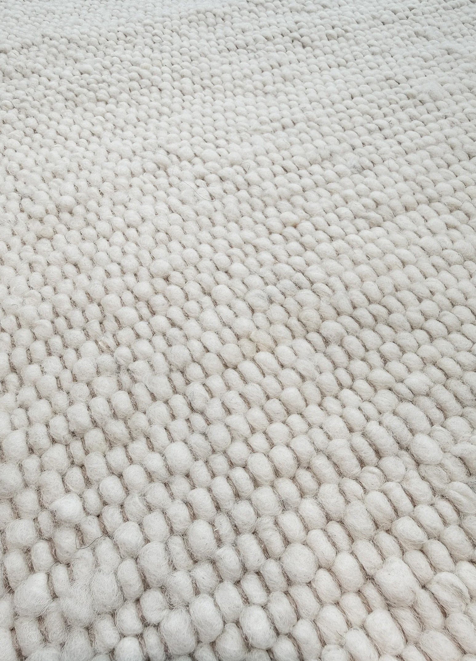 Mellow Ivory kilimo nuotrauka iš arti, kur matosi jo tekstūra su smulkiais šviesiai geltonos spalvos vilnos burbuliukais ir smėlinės spalvos siūlais. Makeyourcasa.lt