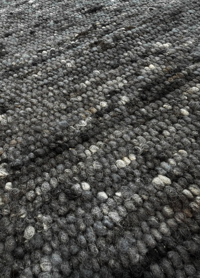 Mellow anthracite kilimas iš arti, kur matoma jo natūralios vilnos tekstūra ir raštas, kuris padarytas iš Vilnos.