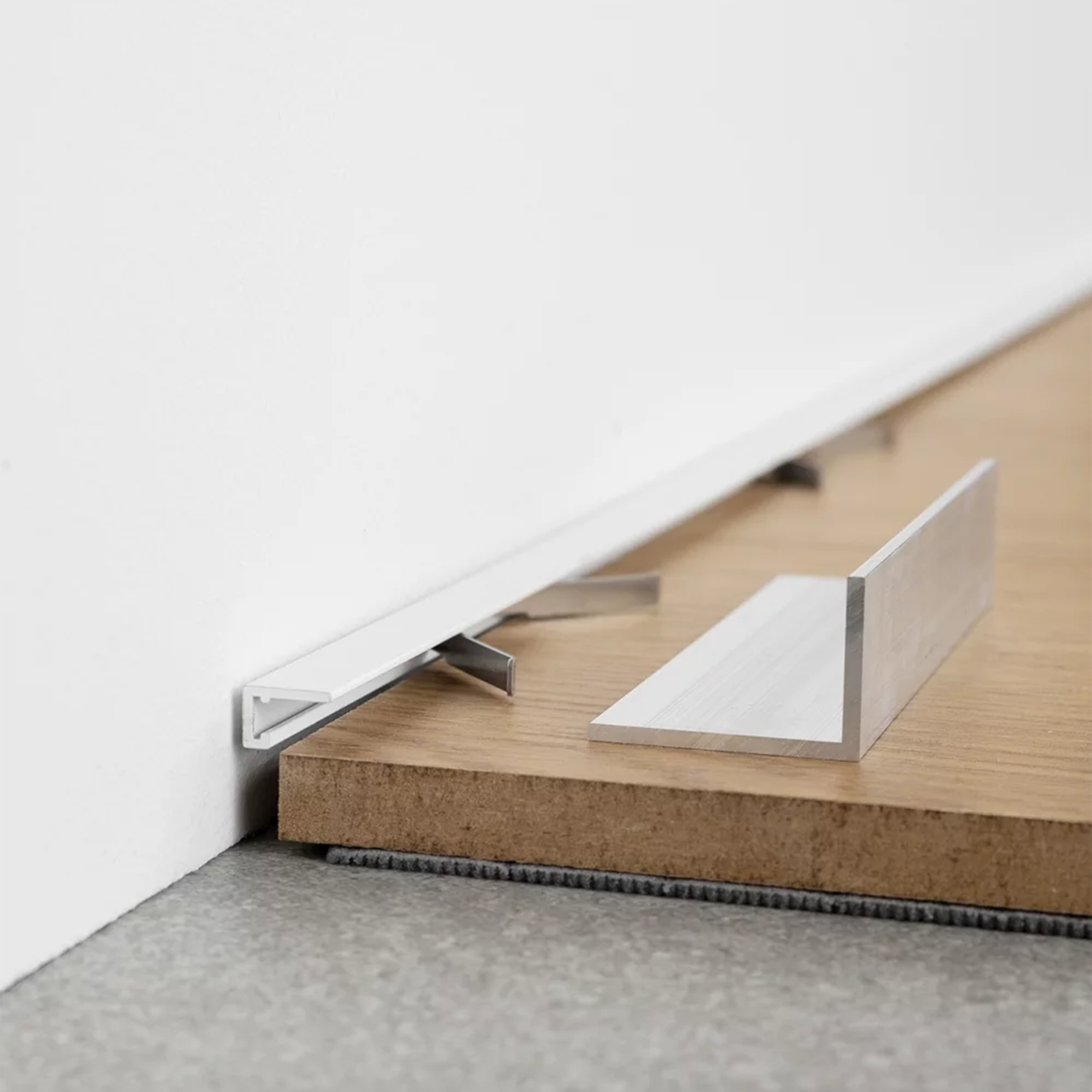 Minimalistinis baltos spalvos plintusas Minileiste, kuris puikiai tinka prie parketo, laminto, vinilo dangos