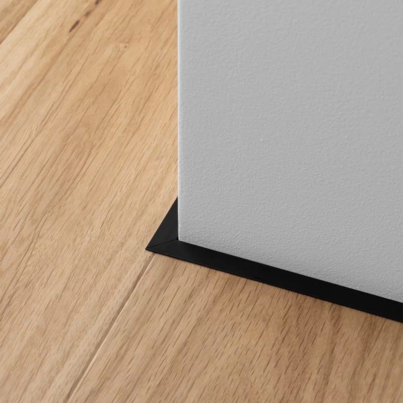 Minimalistinė grindjuostė Minileiste prie šviesios spalvos medžio grindų ir kampo sujungimas | makeyourcasa.lt