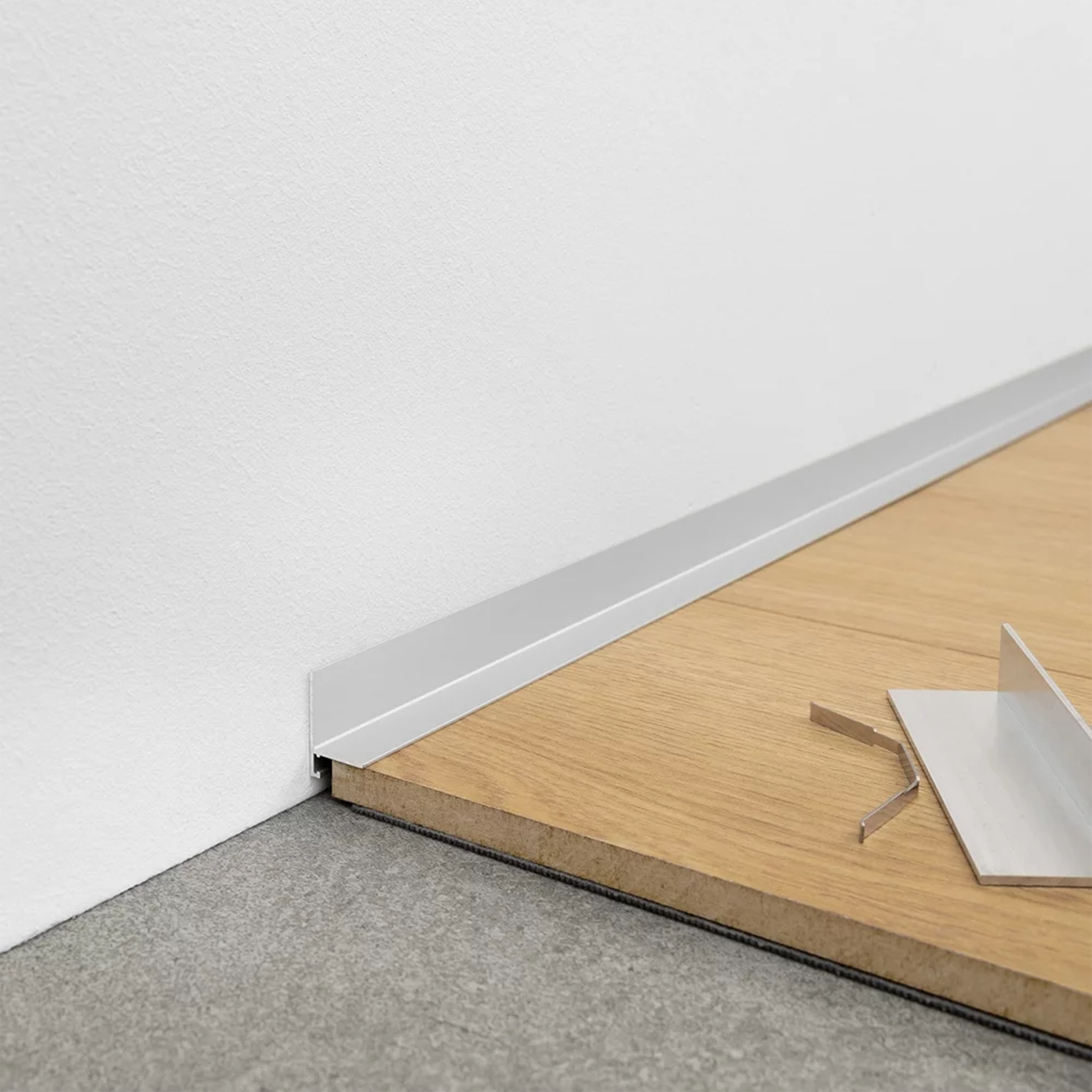 Grindjuostė aliuminė sidabrinės spalvos šalia laminato ir baltos spalvos sienos | makeyourcasa.lt