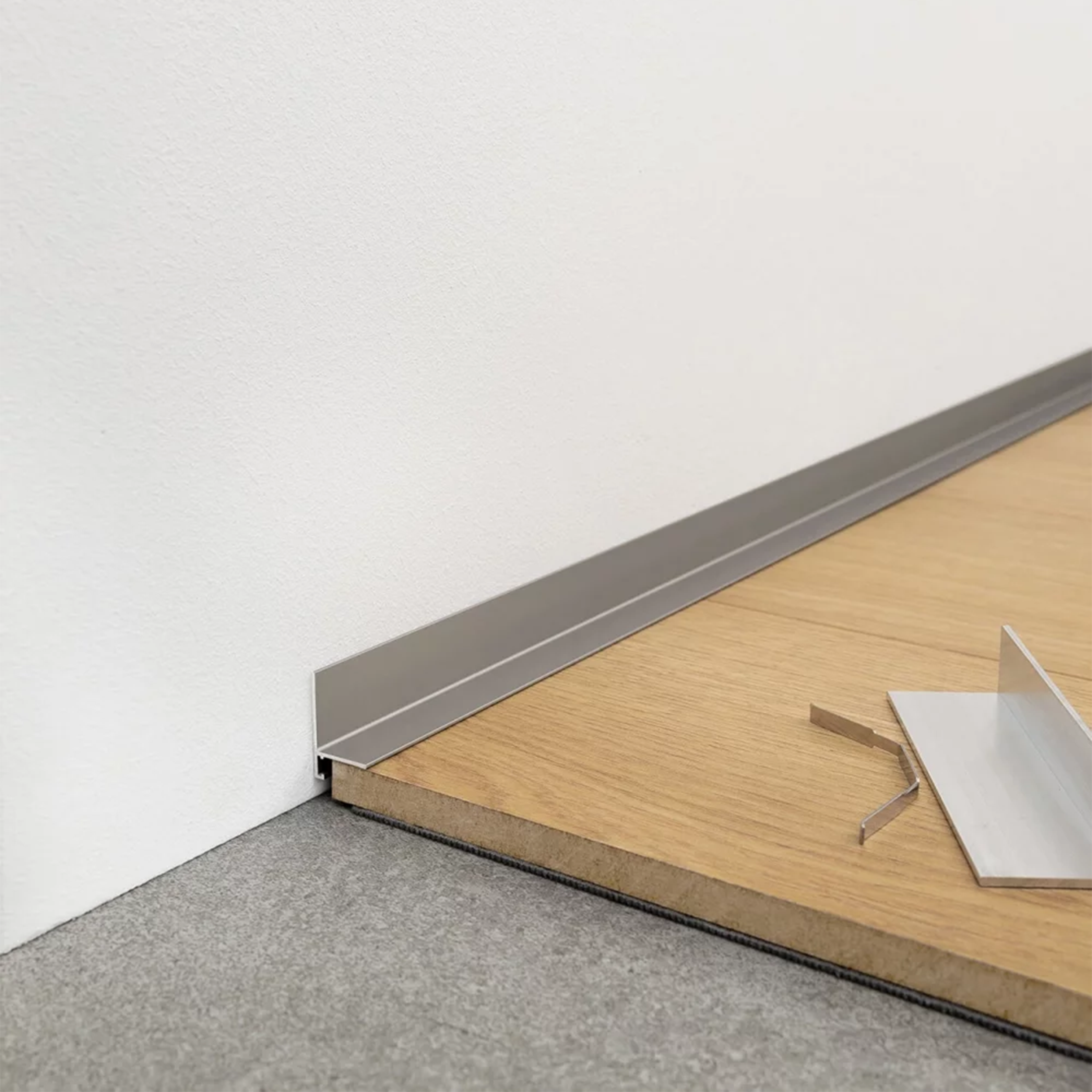 Aliuminė minimalistinė grindjuostė, kuri užtikrina pilna sienų apsauga yra dažyta anodavimo būdų ir yra titaninės brushed nickel spalvos | makeyourcasa.lt