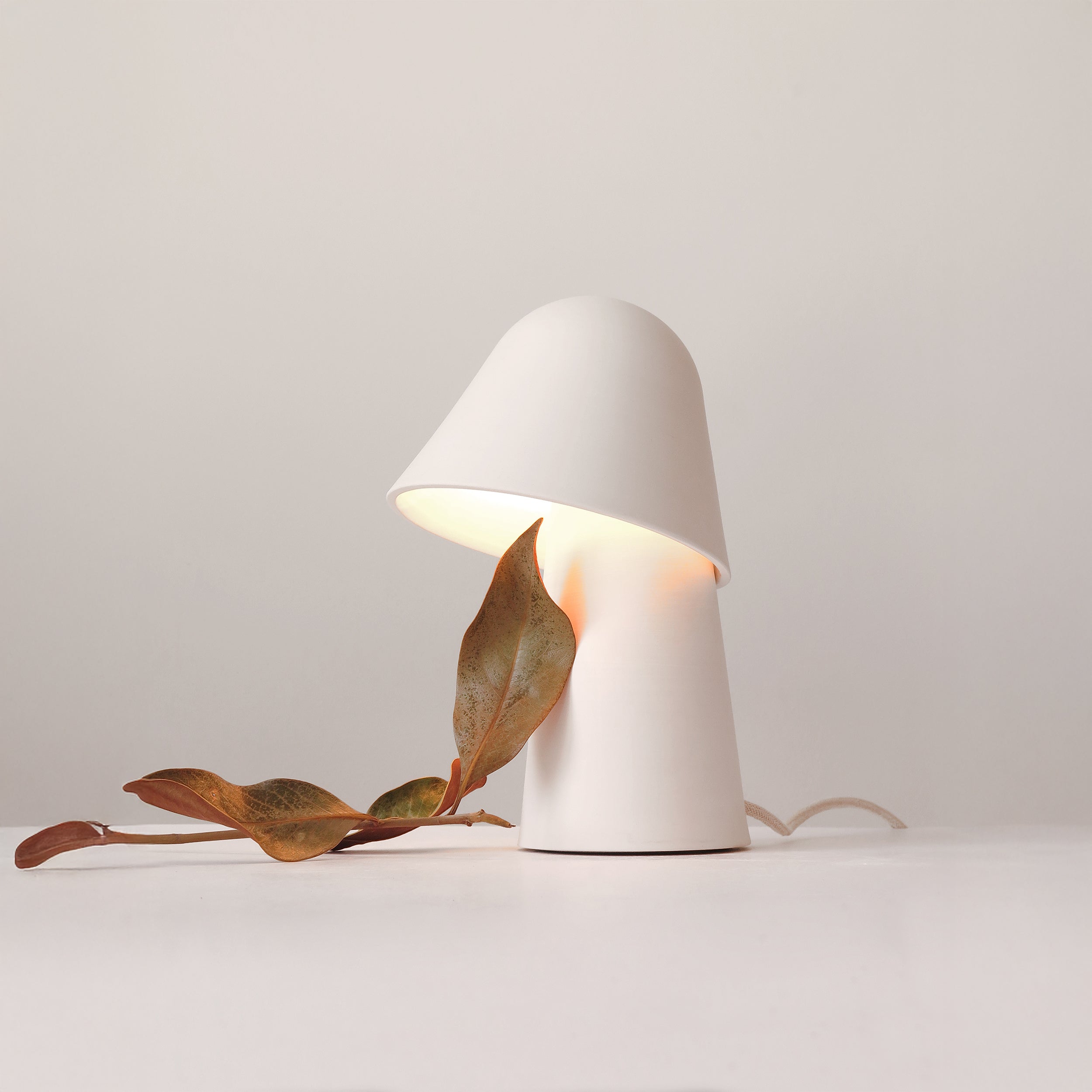 Natūralaus balto molio stalinis šviestuvas pagamintas rankų darbo skleidžia šiltą ir juakią šviesą.