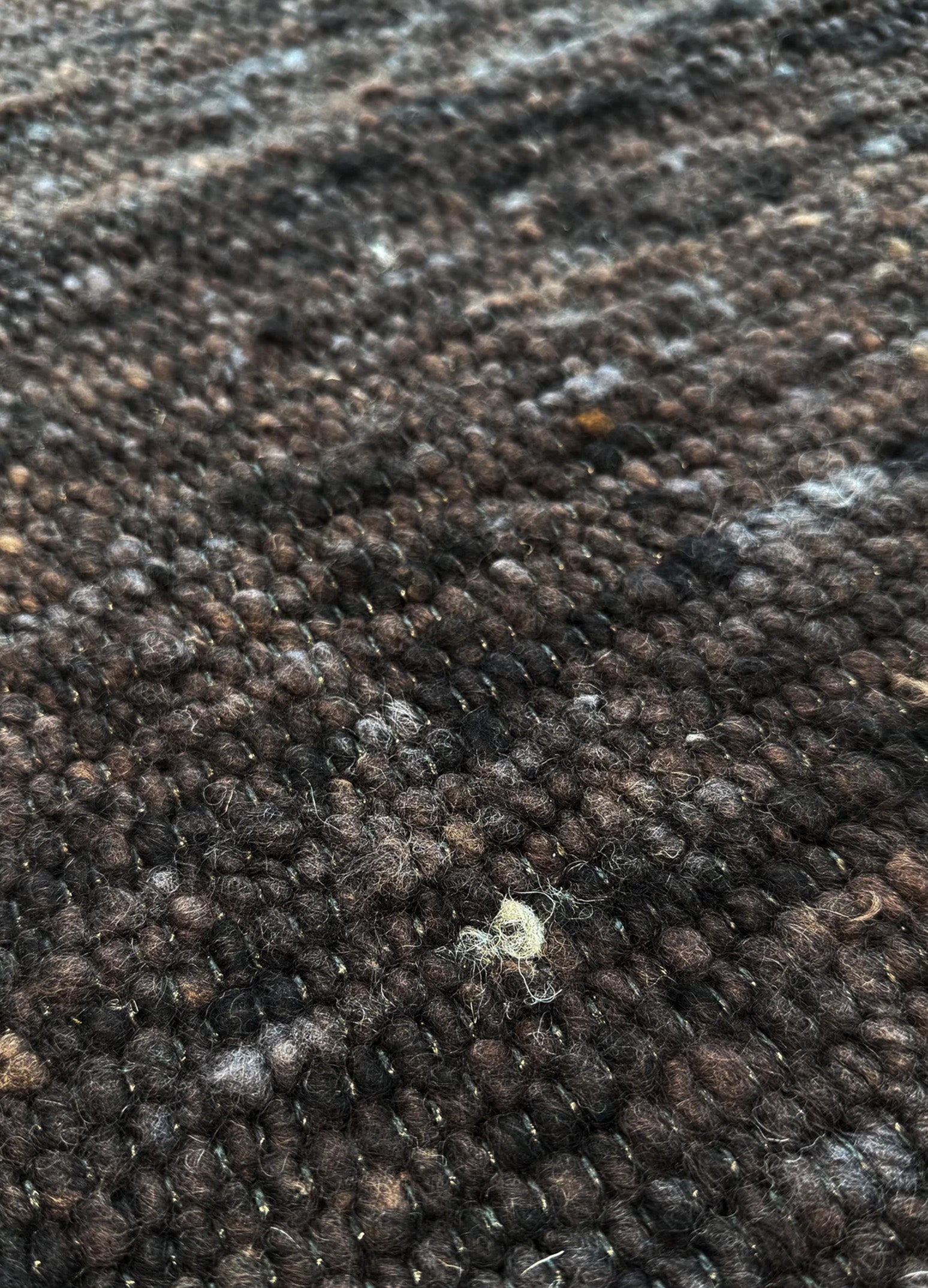 Mellow Brown kilimo tekstūra iš arti, kur matosi visas vilnos raštas ir jo natūrali ruda spalva su keletu šviesesnių ir tamsesnių atspalvių. 